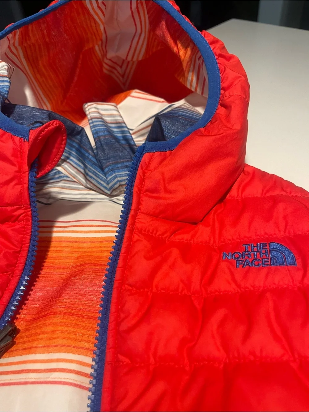 The North Face reversible Solid Red or Vibrant Striped side Puffer Jacket.